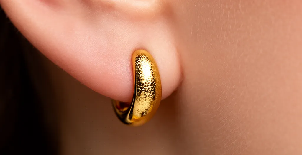 Detailaufnahme von goldenen Ohrringen mit Fokus auf Hautverträglichkeit und Metalllegierungen