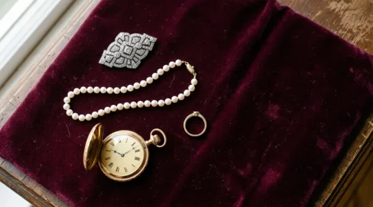 Elegante Schmuckstücke verschiedener Epochen auf antikem Samtstoff arrangiert